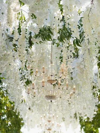 A stunning overhead view of a wedding aisle, with a canopy of hanging white wisteria and crystal chandeliers creating a magical pathway.