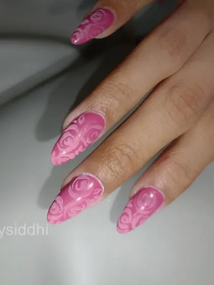 A full set of stiletto nails with a 3D embossed rose pattern in a vibrant pink.