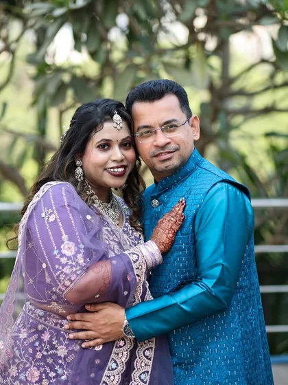 A classic portrait of an engaged couple, smiling warmly for the camera in their traditional attire.