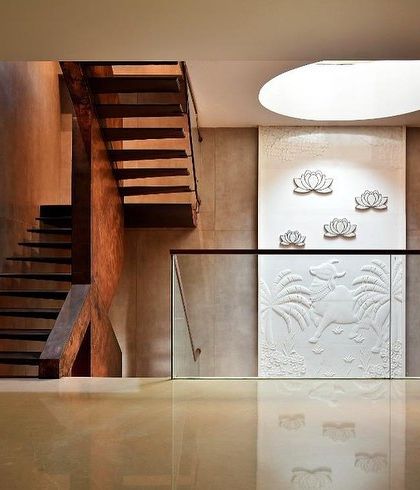 The landing at the top of the stairs, where the circular skylight illuminates the white relief art panel, creating a moment of pause and beauty.