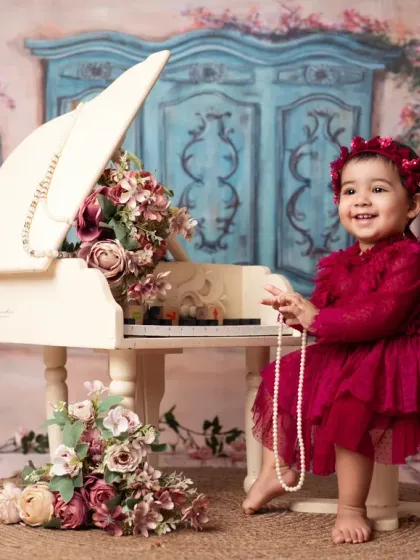 Our studio is filled with unique props like this miniature white piano to create magical, storybook scenes for your child's photoshoot.