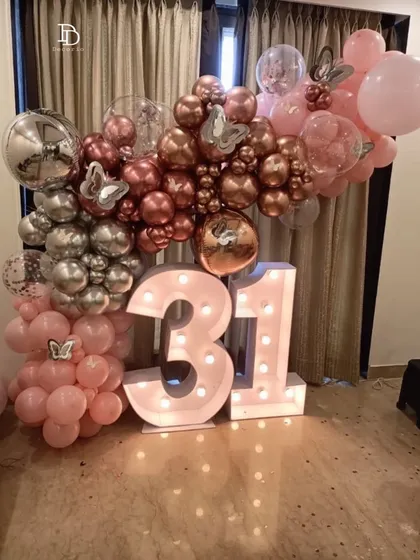 A pretty in pink setup for a 31st birthday. The decor features large '31' marquee numbers surrounded by an arch of pink, rose gold, and silver balloons, creating a celebratory and feminine vibe.