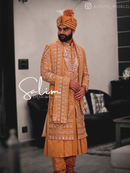 A groom's sherwani in a striking mustard yellow color. The entire garment, including the matching stole, is covered in intricate white threadwork, offering a vibrant yet traditional option for a wedding day.