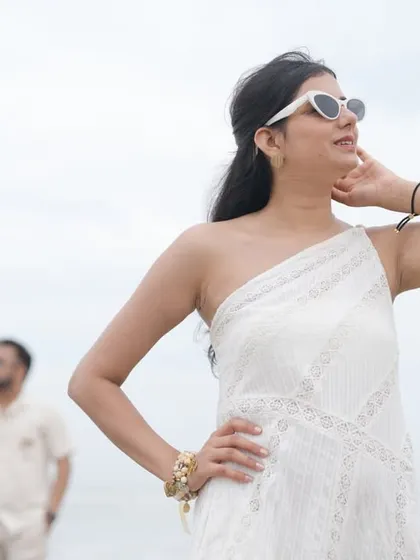 A fashionable solo portrait of the bride on the beach, with the groom in the background. It’s a modern and stylish take on a couple’s portrait.