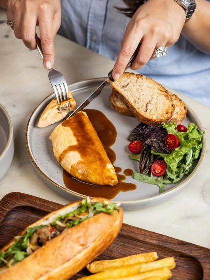 A guest enjoying the Braised Lamb Omelette. It’s a hearty and flavorful dish, perfect for a leisurely Sunday brunch, served here alongside our Bánh Mì.