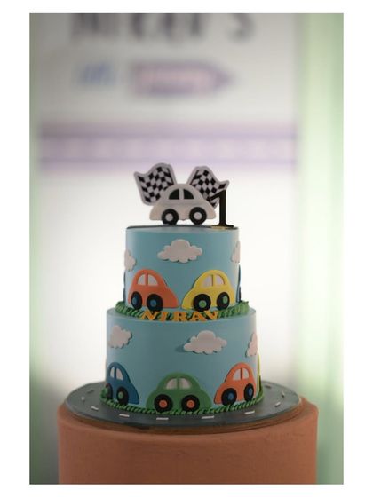 A two-tiered cake decorated with colorful cars, perfect for a little one's transportation-themed birthday.