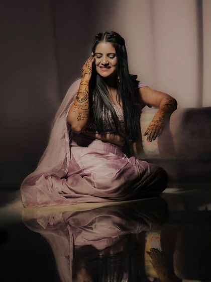 An artistic portrait of a bride, lost in a happy moment during her mehandi photoshoot. Her elegant henna design is a key part of her radiant look.
