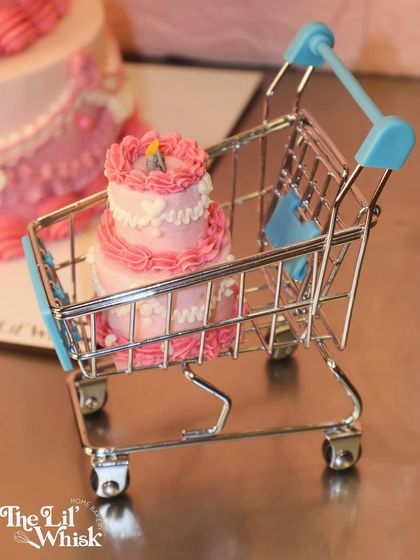 A close-up of the adorable, tiny two-tiered vintage cake sitting inside a miniature shopping cart. It's all in the details.