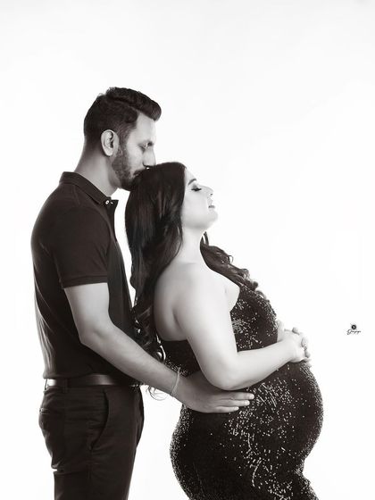 A beautiful black and white portrait capturing a tender moment. The partner's gentle kiss on the forehead is a classic expression of love and care during this special time.