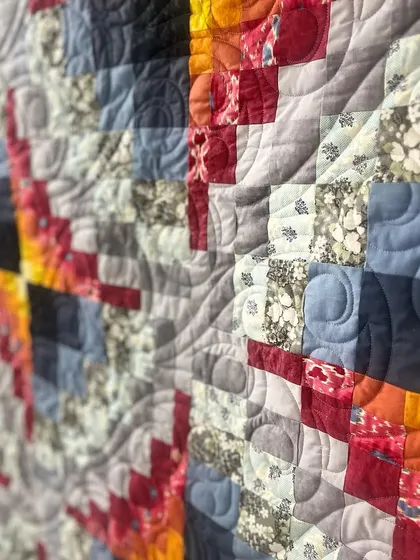 A close-up showing the texture of the quilting on the fiery quilt.