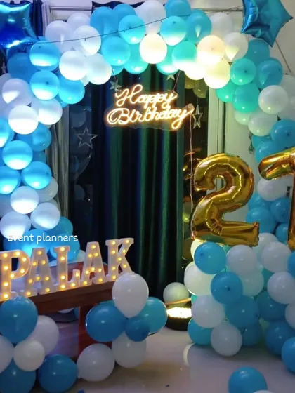 A 21st birthday celebration with a blue and white balloon arch and gold foil numbers.