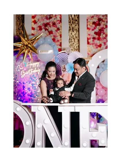 The birthday boy with his parents at his beautifully decorated party. The "ONE" marquee lights add a special touch to this family portrait.