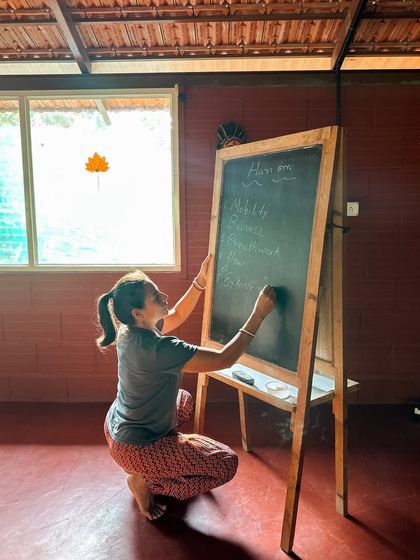 A student writes Sanskrit terms on the blackboard. Learning the language of yoga is a way of honoring its roots and understanding the deeper meaning behind the words we use in class.