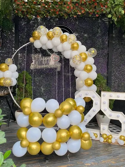 An elegant and classic 25th anniversary decoration. I used a white and gold balloon arch on a circular frame, a hanging 'Happy Anniversary' sign, and large marquee light-up numbers for the '25'.