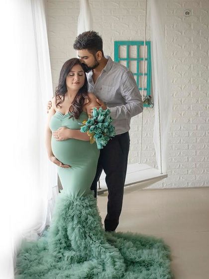 A tender moment between a couple. The flowing mint green mermaid-style gown adds a touch of modern elegance to this classic maternity pose.