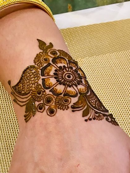 A close-up of a single, modern floral cuff on the wrist. This is a great option for someone who wants a small, bracelet-like henna design.