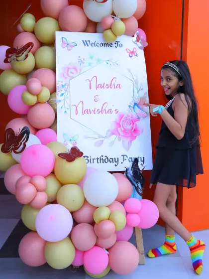 A guest points to the welcome sign at a butterfly and floral-themed birthday party. The elegant design is perfect for a sophisticated celebration.