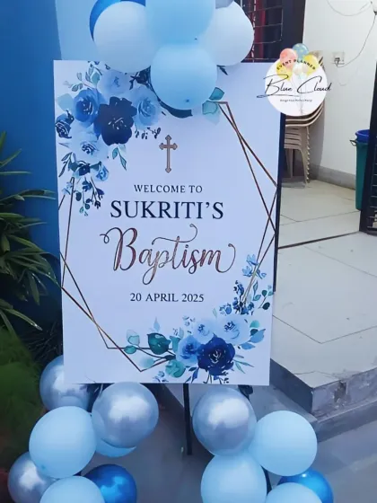 A personalized welcome sign for Sukriti's Baptism, framed with blue and silver balloons.