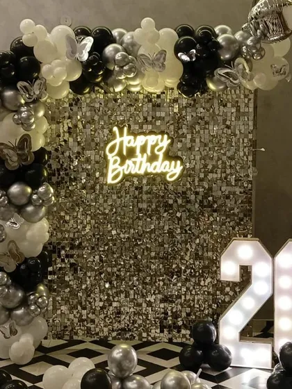 A chic and modern party backdrop featuring a silver shimmer wall and a black, white, and silver balloon arrangement. While this setup displays a "Happy Birthday" sign and the number 26, I can customize it for any anniversary with the right text and numbers.