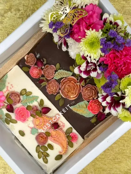 A closer look at the 'Bloom with Gratitude' hamper, showcasing the two distinct, beautifully decorated artisanal chocolate bars nestled next to a fresh flower arrangement.