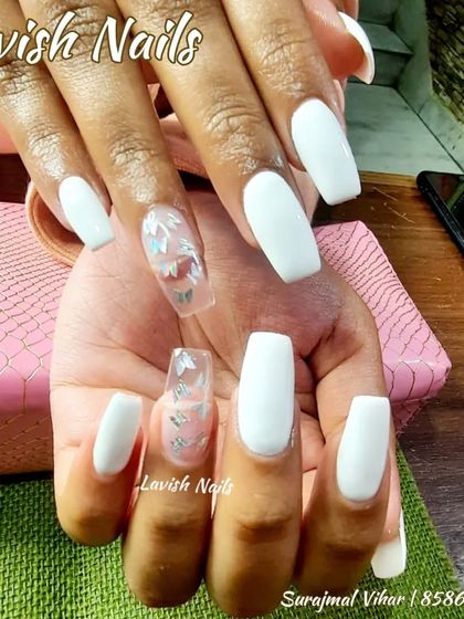 Long, white coffin nails with a clear accent nail featuring delicate silver butterfly decals.
