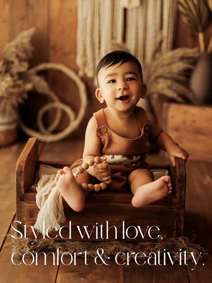 Styled with love, comfort, and creativity. This baby is sitting on a miniature wooden bed in a beautiful boho-themed setup, complete with natural textures and pampas grass.