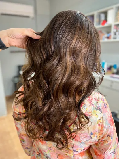 A beautiful sunkissed balayage that adds brightness and dimension. The soft curls enhance the multi-tonal effect.