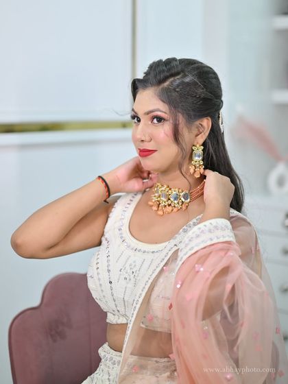 A portrait of the model in the white chikankari lehenga, adjusting her modern choker. This is a fresh and youthful look for a day wedding.