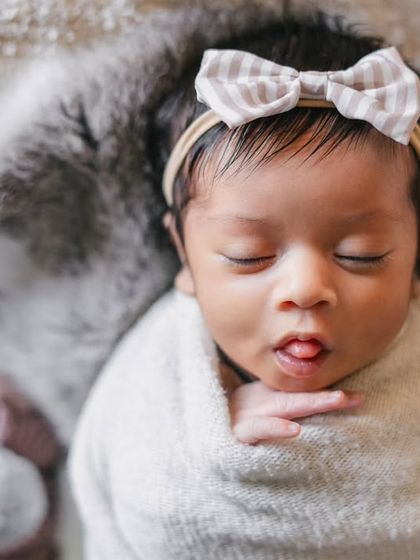 Even in sleep, newborns make the cutest faces. This close-up captures a tiny tongue-out moment, a perfect detail of this baby girl's personality.