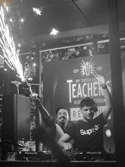 A celebratory black and white shot with sparklers going off behind the DJ booth at Raahi.