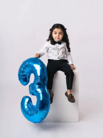 A classic portrait of a stylish three-year-old. He looks so grown up and charming sitting with his birthday balloon.