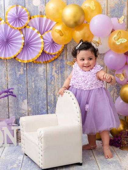 Celebrating one year with a lovely lavender and gold theme. This little girl stands proudly by her chair, ready for her party.