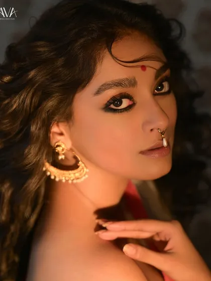 A striking close-up portrait for a 'Shubho Noboborsho' campaign. The model's intense gaze, bold kohl-rimmed eyes, and traditional nose ring create a powerful and dramatic look.