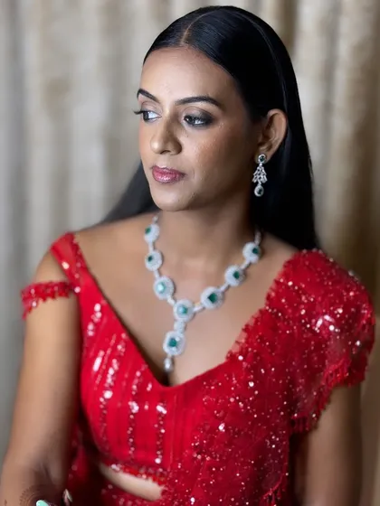 For her sister's reception, Aruna wanted a bold and glamorous look. We chose a classic red saree and paired it with a sleek hairstyle and defined, smoky eyes for that perfect Bollywood-inspired party look.