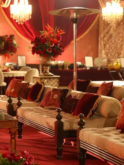 Another view of the lounge area, showing the rich red drapes, tufted diwan seating, and elegant floral arrangements that created a warm and inviting atmosphere.