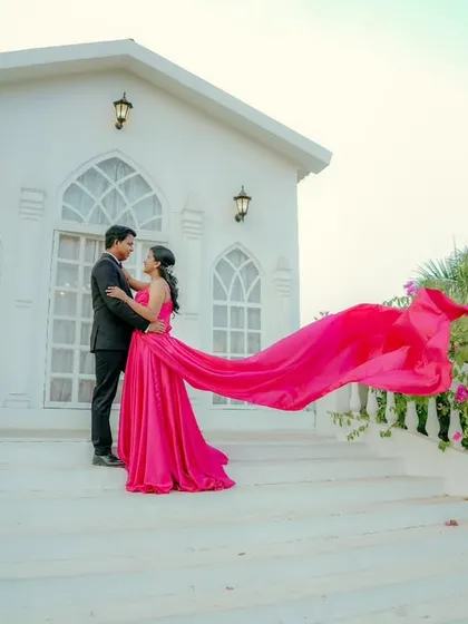 A stunning, wind-swept shot. The bride-to-be's long pink gown flows beautifully in the air, adding drama and movement to this pre-wedding photo.