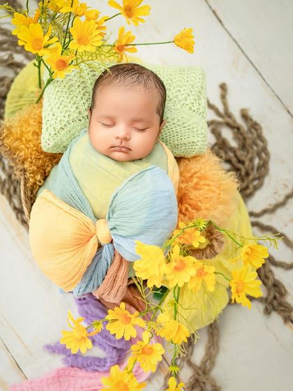 Our little butterfly. The bright yellow flowers and colorful wrap create a cheerful and beautiful spring-themed portrait.