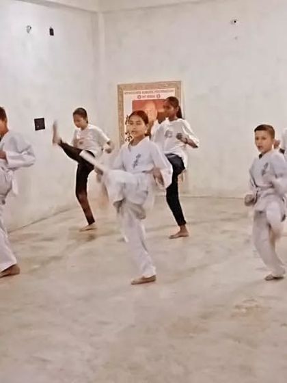 A student achieves a high kick, showing great flexibility and control.