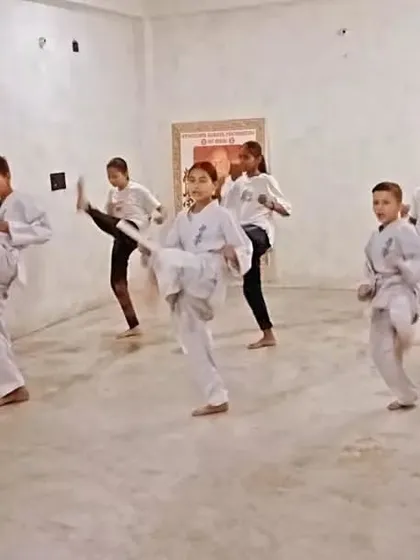 A student achieves a high kick, showing great flexibility and control.