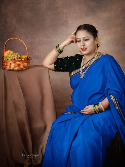 A thoughtful and artistic pose. This mom-to-be in a vibrant blue saree looks like she is pondering the future, creating a deep and emotional portrait.