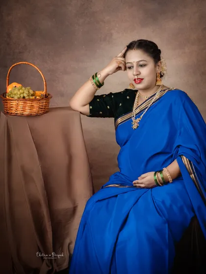 A thoughtful and artistic pose. This mom-to-be in a vibrant blue saree looks like she is pondering the future, creating a deep and emotional portrait.