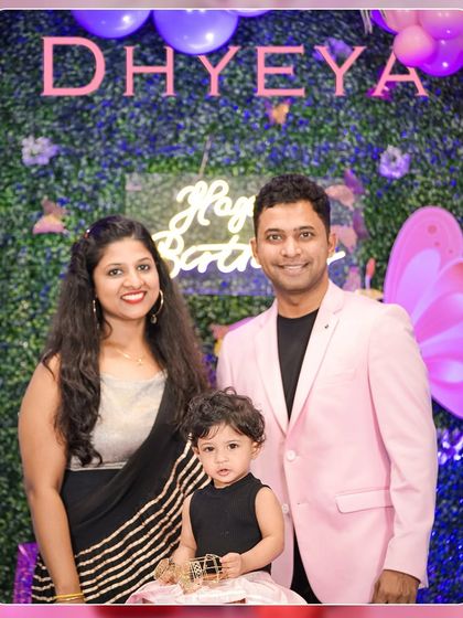 A lovely family portrait from a first birthday party, capturing the proud parents with their one-year-old daughter.