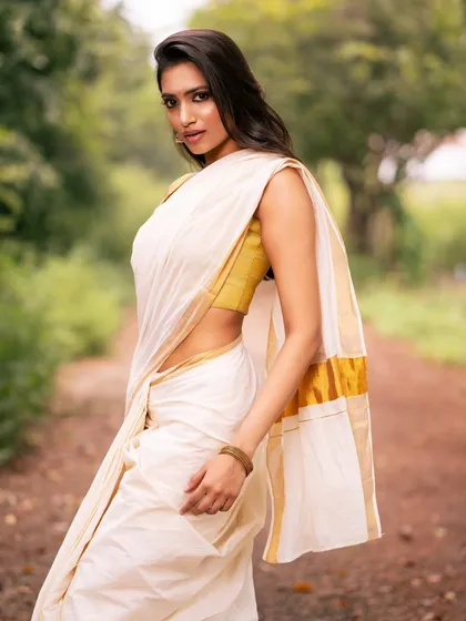 A profile shot of a model in a white and gold saree, capturing a moment of quiet elegance.