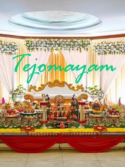 A wide view of a half-saree function setup with a red and white theme, showing the full stage and the elaborate plate arrangements.