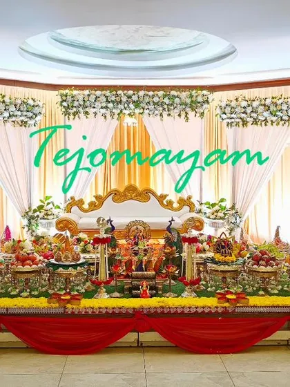 A full-stage view of a Half-Saree function decoration, with a simple white and red backdrop and a colorful plate display.