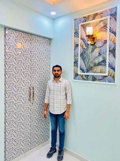 Standing in the blue-themed bedroom, showcasing the custom wardrobe and the decorative wall panel.