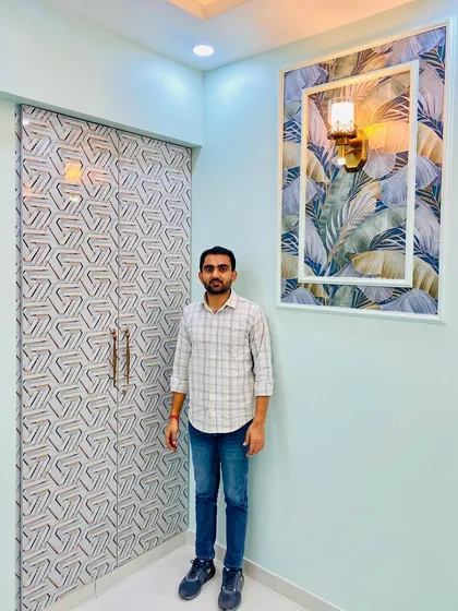 Standing in the blue-themed bedroom, showcasing the custom wardrobe and the decorative wall panel.