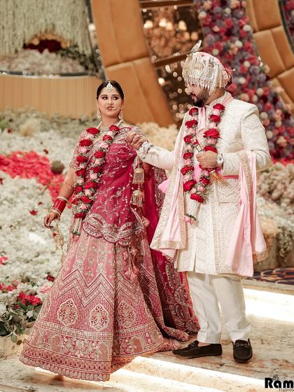 A grand walking shot of the couple on a stage decorated with a mountain of flowers, showcasing the scale and beauty of their wedding decor.