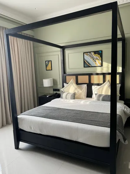 A side view of the black four-poster bed, showing its clean, minimalist frame that reinterprets a classic design.