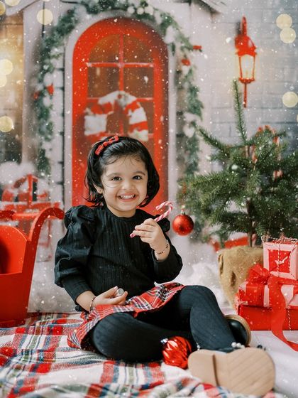 A little girl smiling with her candy cane in our festive Christmas setup. Pure holiday joy.